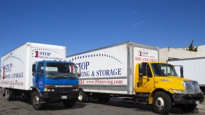 Two One Stop Moving & Storage long-distance moving trucks parked under a clear blue San Diego sky