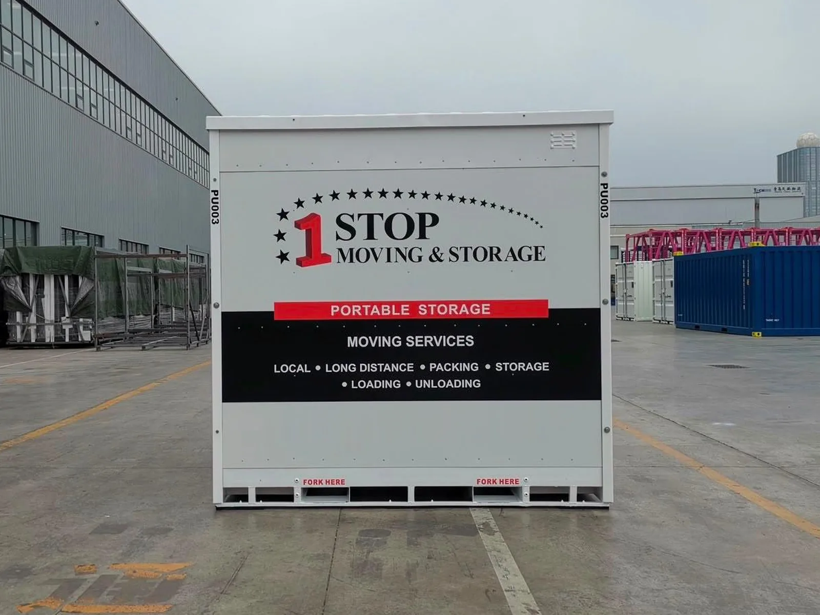 A 1-Box steel portable storage container photographed head-on with its doors closed, standing on the factory apron. Its side still carries One Stop Moving & Storage lettering.